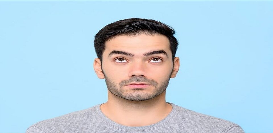 Young man looking upward against blue background